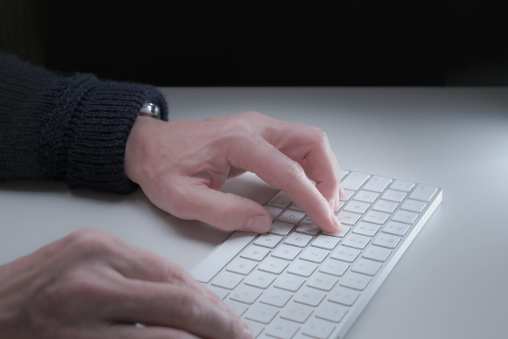 zwei Hände tippen eine Nachricht auf einer Tastatur
